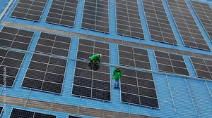 Worker Technicians are working to construct solar panels system on roof. Installing solar photovoltaic panel system. Men technicians carrying photovoltaic solar modules on roof.
