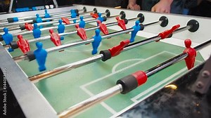 Kick off strike in table football game. Young people playing foosball. Side view