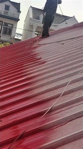 painting the metal roof surface with red spray paint to protect it from rust and weather