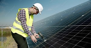 Connection and mounting of solar panels. Technician connecting solar panel. Technician working with electrical screwdriver installing solar panel to metal platform system. Installation.
