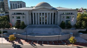 American and Alabama flags at rest. AL state government court building. Courthouse dome and columns at entrance.