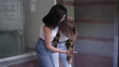 Angry Caucasian teen girl showing smartphone to classmate pushing...