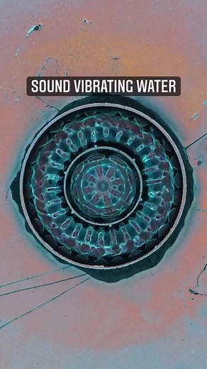 The physics of sound made visible. The cap of water is attached to small platform on a vibrating speaker. Coloured light is reflected from above. What we are seeing here is the reflected light on the waters surface. Once vibrating, it creates waves on the surface of the water, as peaks and troughs. The peaks and troughs of the water reflect the light differently, so through this we can see where and how the waves are moving. The waves move out from the centre, hit the edge, and then reflect back