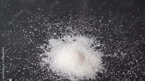 granulated sugar. pouring sugar on a black background.