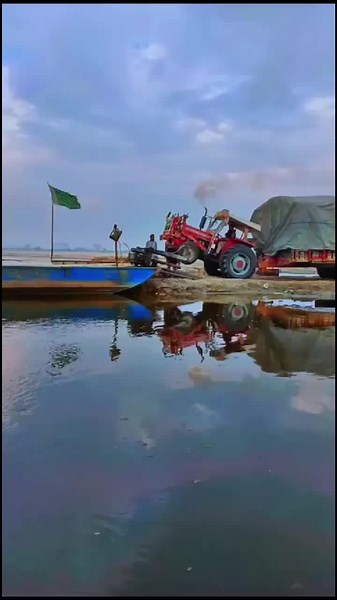 Red Tractor Towing A Blue Boat On Water