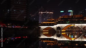 tilt up view at night of Chengdu capital city of the Chinese province of Sichuan, Anshun Bridge over the Jin river with modern skyline skyscraper building