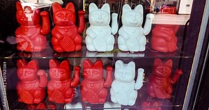 Maneki neko also known as chinese fortune cat. Showcase with welcoming souvenir cats beckoning to enter