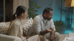 PAN shot of diverse family couple sitting on sofa and having emotional argument while African American psychologist trying to calm them down during therapy session