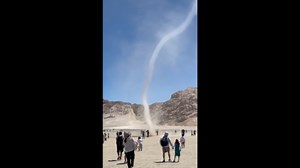 Dust devil tornado winds through tourists in desert