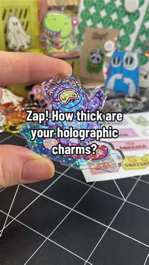 Zap! How thick are your holographic charms? Our holographic acrylic charms are made from 2 layers of 2mm clear acrylic, with an overall thickness of 4mm. The artwork layer is sandwiched between 2 layers of clear acrylic. #merch #charms #holographic #custom #accessories