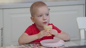 3-year-old child licking ice cream in a waffle cup at home