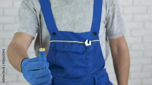 Handyman shows a screwdriver. A man builder holds out his hand with a screwdriver.