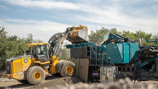 Heavy wheel loader operating aggregate processing equipment