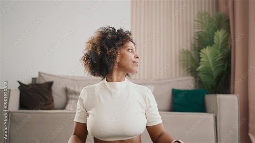 Morning workout at home for good body conditions, black woman doing gymnastics. Exercises for neck flexible and prevention of osteochondrosis, portrait of african american lady training calmly alone