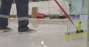 A builder is applying polymer floors using Scraper Float. A builder distributes resin flooring material evenly using a Scraper Float. The process of creating polymer floors
