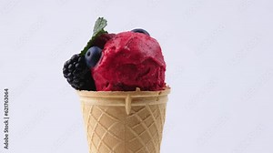 Ice cream cone with an assortment of fruits and ice cream flavors, rotating on a table. Homemade raspberry and vanilla ice cream in cups. Food and advertising concept