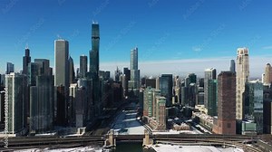 Aerial view over the icy Chicago river, towards sunny Streeterville and River North districts, winter in Illinois, USA