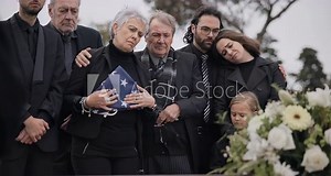 Funeral, graveyard and sad family with American flag for veteran for comfort, ceremony and memorial service. War hero, depression and people by coffin in cemetery mourning military, army and soldier