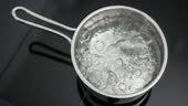 Water boiling in a small pan. Shot from up and in slow motion.