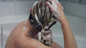 Woman cleaning hair with shampoo in bath. She is shampooning hair.