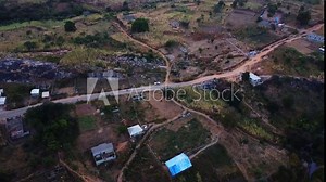 Aerial of a a beautiful Nigerian countryside with a few buildings and structures alongside a road crossing through a national park near Abuja, the capital of the African country
