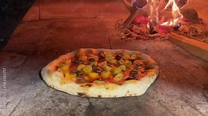 Vegetarian pizza with high crust being cooked in a wood oven. Real fire burning in the background. Cornice that grows during cooking.
