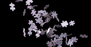 White puzzle pieces falling down whirling in slow motion on a black background