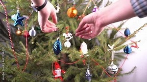 Christmas tree at home. Decor. Green coniferous branches close up. Decorate the Christmas tree with toys and balls. New Years Eve. Home life. Simple miscellaneous toys. Hands hang the toy.