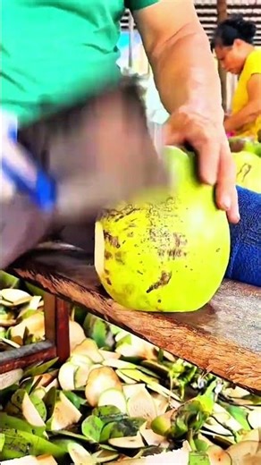 Coconut being cut open with large knife on wooden table