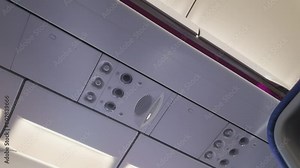 The overhead panel of an airplane cabin, featuring air vents, lighting controls, and possibly an announcement speaker system, capturing a common sight for travelers.