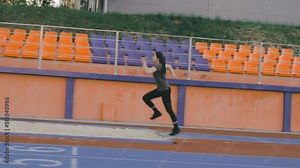 A sporty runner athlete woman runs up at a stadium and performs a long jump in slow motion in a stadium