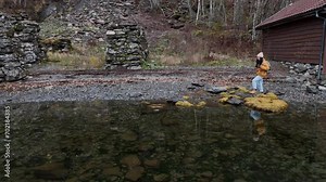 A happy yellow sporty backpacker woman before the rain, prepare for the adventure on the cliff fjord during the trip to Norway. Trolltunga hiking route