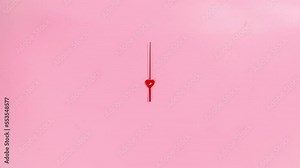 4k The red hand of the clock rotates in a circle. Pink background. The concept of the transience of time. Heart in the center. Stop motion animation. Copy space. Flat lay.