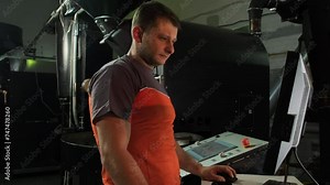 Operator prepares roasting machine using computer. Experienced worker carefully checks necessary settings for effective work