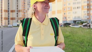 Delivery of pizza and food to home. Smiling delivery man in uniform carrying pizza boxes in his hands walks down street in big city delivering order to customers and clients.