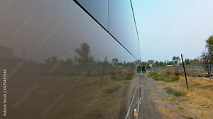 Side view of a public bus, shuttle, or school bus driving and the road reflection on it. Bus turning slowly on a country road and driving straight