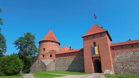 Trakai Castle Flanked by Stone Walls and Green Trees Under a Clear Blue Sky in Lithuania Stock Footage - Video of roofs, landmark: 390583504