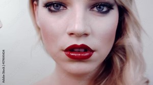 Beautiful girl holds lipstick in front her,opens her lipstick,looks into camera, smiles.Shows red lipstick.In studio on white background.Beauty salon.Hairstyle retro style,hollywood wave,bright makeup