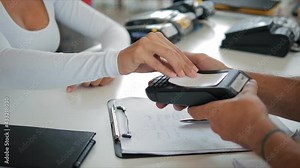 Hand of customer paying with contactless credit card with NFC technology. Bartender with a credit card reader machine at bar counter with female holding credit card. Focus on hands