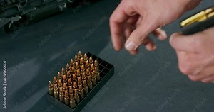 Close-up of male hands loading bullets into a gun magazine clip at a firing range. Stock Video
