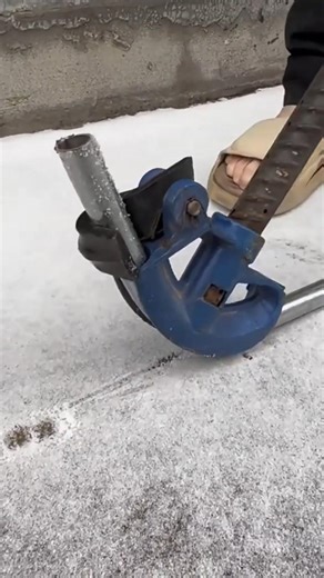 bending a long hollow metal pipe precisely into a specific curve using a blue manual bending tool