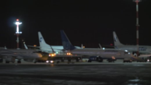 A blurred panoramic shot of airplanes on an airport courtyard at night | Premium Stock Video Footage