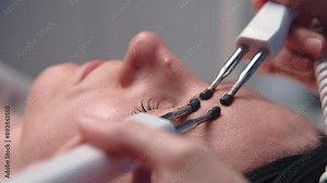 Close-up portrait of a beautiful woman with closed eyes and a skin rejuvenation machine. Salon procedures. Microcurrent therapy