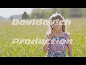 Beautiful blond little girl eats ice-cream in the summer next to the wheat field. Warm sunny day