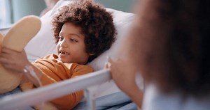 Boy, hospital and teddy bear in bed with smile, recovery and help for patient with mom on bedside for support. Treatment, iv drip and hand for healthcare, toy and rehabilitation in pediatric care