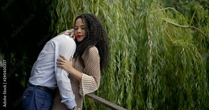 man is hugging and kissing his beloved girlfriend, snuggling her to fence in park