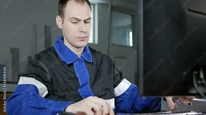 Male engineer measures the item and enter the data into a computer program CNC machines. Work clothes, calipers in his hands. On the background materials for production.