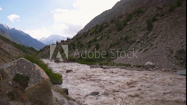 Slow motion shot of flooded Miyar river flowing in between the Himalayan mountains after heavy rain as seen from Miyar Valley in Lahaul, Himachal Pradesh, India. Raging river after heavy rains.
