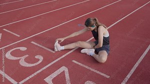 Female runner stretches her muscles in preparation for running on the treadmill around the soccer field.
