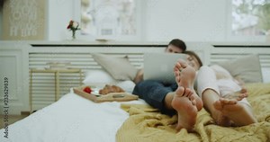 Spending romantic time together young couple in the morning watching something from notebook in bed.